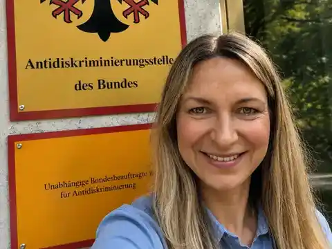 Sarah Perry vor dem Schild der Antidiskriminierungsstelle des Bundes